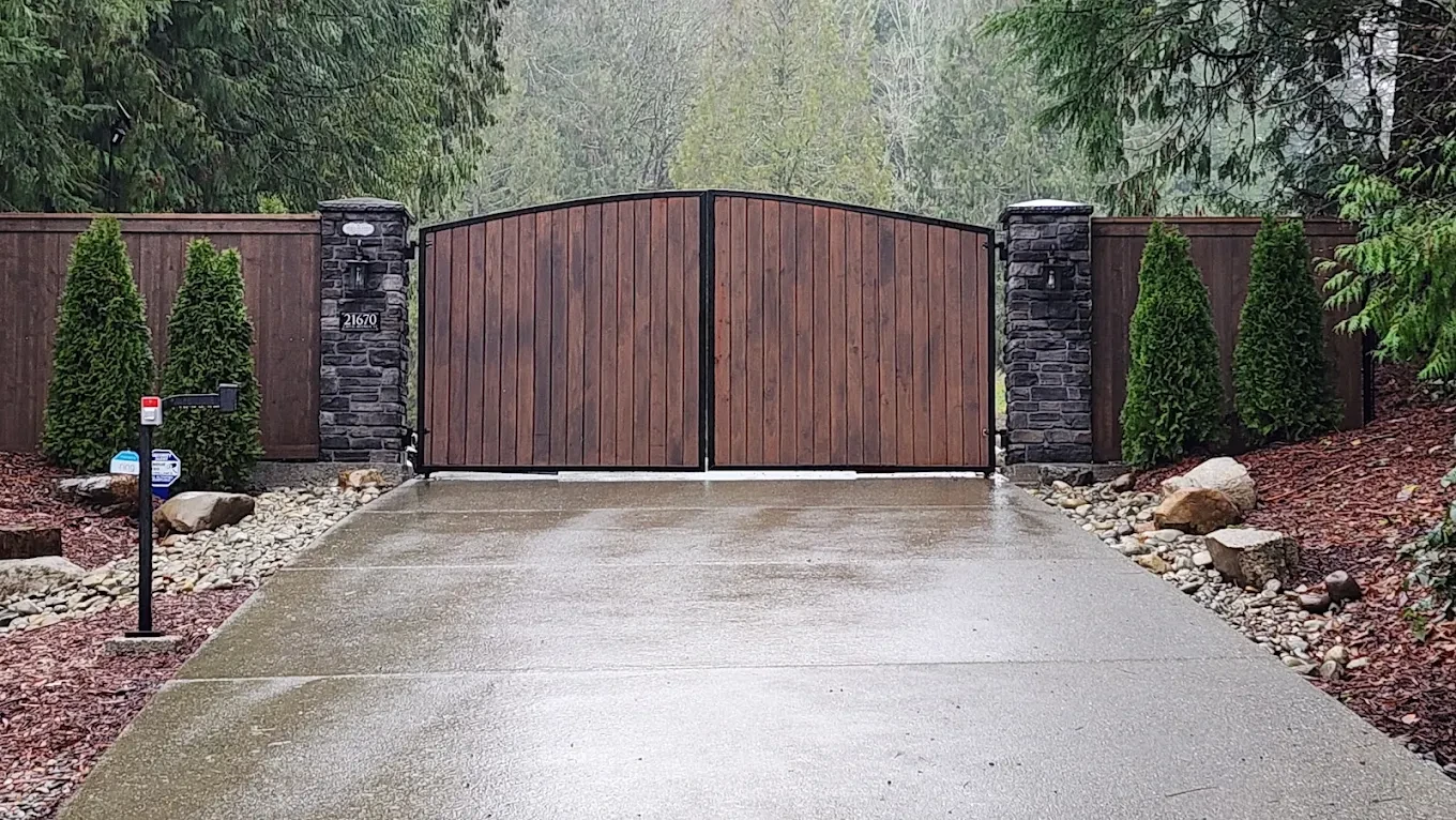 Metal driveway gate with stone pillars